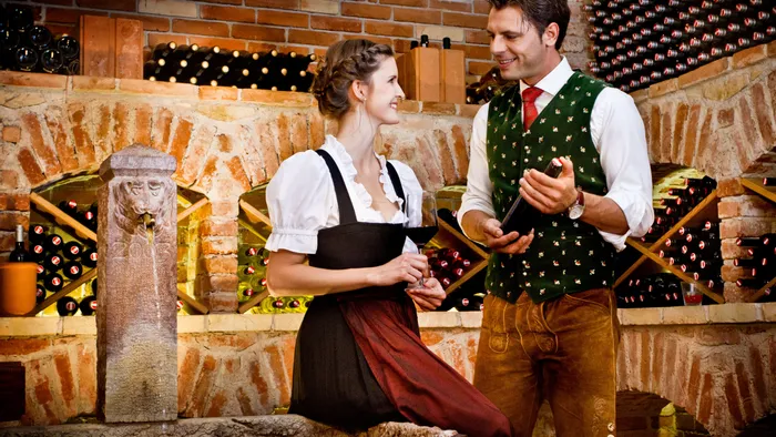 Paar in traditioneller Tracht genießt Wein in rustikalem Weinkeller